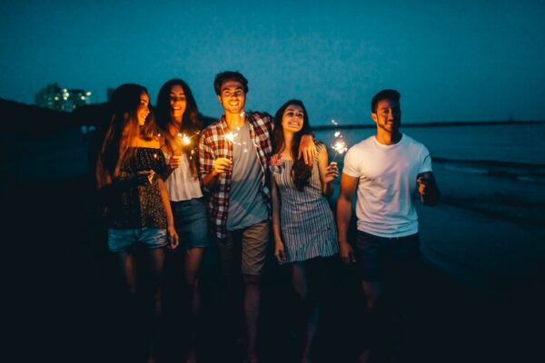 friends with sparklers walking by the beach